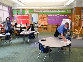 A man sanitizes tabletop surfaces in a kindergarten classroom at Hunter's Glen Junior Public School during the COVID-19 pandemic in Scarborough, Ont., on Monday, Sept. 14, 2020.