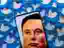 An image of Elon Musk is seen on a smartphone placed on printed Twitter logos in this picture illustration.  