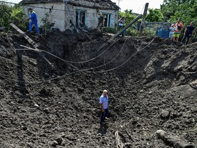 Ein Mann steht in einem Krater, der durch einen russischen Raketenangriff in der Siedlung Kushuhum hinterlassen wurde, während Russlands Angriff auf die Ukraine in der Region Saporischschja, Ukraine, am 10. August 2022 fortgesetzt wird.