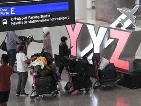 People wait with their luggage at Pearson International Airport in Toronto on Friday, August 5, 2022.
