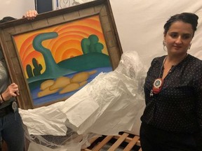Policia Civil investigator and a delegate hold a painting titled "Sol Poente" after it was seized during a police operation in Rio de Janeiro.