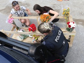 Kailey Graham (in white) and her friend Kayleigh Bryant-Nordeen showed up with flowers for six young adults who were all killed sometime over the weekend in the Barrie area. It is believed they were travelling along McKay Rd. W. near Veterans Dr. when they collided into a excavated hole in the road.
