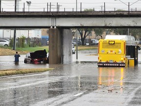 This handout photo provided by the Dallas Police Department on Aug. 22, 2022, shows people standing next to a vehicle sitting in flood waters, along a street in Dallas, Texas.