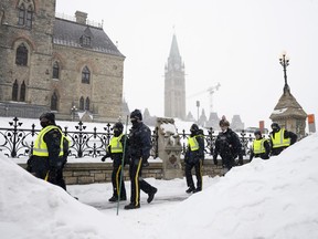 Police officers walk pass the Parliament buildings after a protest in Ottawa on Sunday, Feb. 20, 2022.