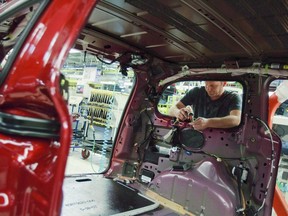 A worker installs parts on the production line at Chrysler's plant, in Windsor, Ont., Jan. 18, 2011.