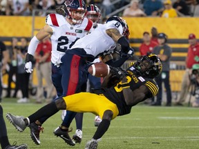 Hamilton Tiger Cats wide receiver Steven Dunbar Jr. (8) loses the ball after being hit hard by Montreal Alouettes corner back Mike Jones (8) during second half CFL football game action in Hamilton, Ont. on Thursday, July 28, 2022.