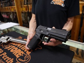 Salesman Chris Ruegg displays a Sig Sauer P320 9mm handgun from the display case at That Hunting Store on June 3, 2022 in Ottawa.