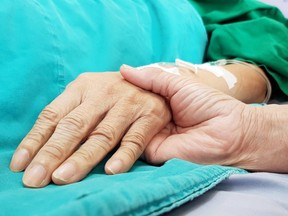 Oncologist doctor holding patient's hand in hospital. Showing all love, empathy, helping and encouragement. He has end stage cancer disease. Healthcare in end of life and palliative care concept