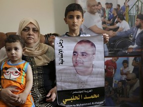 Amal el-Halabi hält ihren Enkel Fares, während ihr Enkel Amro, 7, am 8. August 2016 ein Bild seines Vaters Mohammed el-Halabi, Gaza-Direktor der internationalen Wohltätigkeitsorganisation World Vision, in seinem Familienhaus in Gaza-Stadt hält.