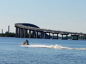 A rider on a personal watercraft enjoys the waters of the Calcasieu River with the Israel LaFleur Bridge in the background.