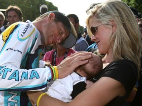 Lance Armstrong of the United States looks at his baby Max as his girlfriend Anna Hansen looks on on July 26, 2009 on the famous Champs-Elysees Avenue in Paris.