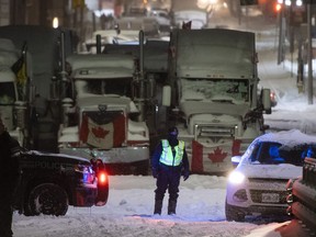 An Ontario Provincial Police officer mans a roadblock along Wellington Street, as a winter storm warning was in effect, on the 22nd day of a protest against COVID-19 measures that had grown into a broader anti-government protest in Ottawa on Friday, Feb. 18, 2022.