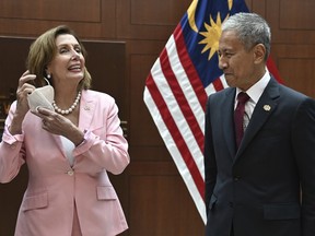 This handout photo taken and released by Malaysia's Department of Information, U.S. House Speaker Nancy Pelosi, left, removes her face mask as she meets with Malaysia Parliament speaker Azhar Azizan Harun at the parliament house in Kuala Lumpur, Tuesday, Aug. 2, 2022.