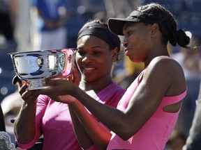 Serena Williams, left, and her sister Venus examine the championship trophy after winning the U.S. Open in New York, Monday, Sept. 14, 2009.