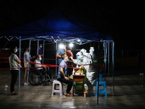 Medical workers in protective suits collect swabs from residents at a nucleic acid testing site following COVID-19 outbreak in Guiyang, Guizhou province, China, Sept. 9, 2022.