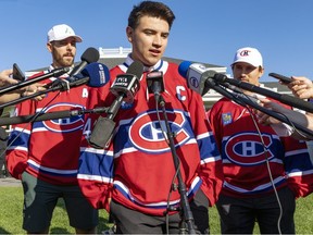 Montreal Canadiens Nick Suzuki is flanked by assistant captains Joel Edmondson, left, and Brendan Gallagher after being named the team's latest captain at their annual golf tournament in Laval, north of Montreal Sunday September 11, 2022.