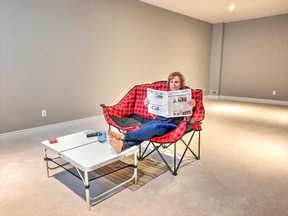Dee-Anne ‘camps out’ in her new rec room decorated only by a portable loveseat and table, forced into a Plan B because the home they left needs to be staged as long as possible.