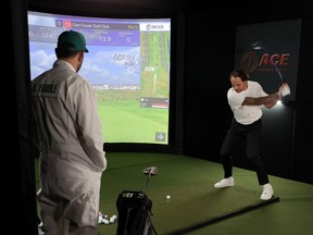 With fellow NHL star Keith Yandle (left), dressed as a caddie and watching, Auston Matthews of the  Maple Leafs take a swing at a golf simulator during the 2022 NHL players media tour in Las Vegas.