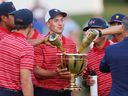 (L-R) Jordan Spieth of the United States Team holds the Presidents Cup for teammates during the closing ceremony after defeating the International Team during Sunday singles matches on day four of the 2022 Presidents Cup at Quail Hollow Country Club on September 25, 2022 in Charlotte, North Carolina. 