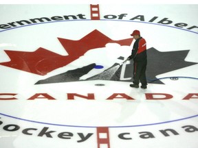 Ice Technician Ryan Smith (with hose) and Blayne Sproule prepare the ice over top of a Team Canada logo on the Calgary Flames locker room on Aug 21/ 09 as Hockey Canada prepares to take over the Pengrowth Saddledome for the team Canada Olympic Camp next week.