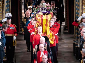 The Bearer Party of The Queen's Company, 1st Battalion Grenadier Guards, carry the coffin of Queen Elizabeth II, draped in a Royal Standard and adorned with the Imperial State Crown and the Sovereign's orb and sceptre inside St George's Chapel at Windsor Castle at the Committal Service on September 19, 2022.
