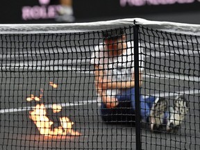 A protester invades the court, appearing set his arm alight during the singles game between Greece's Stefanos Tsitsipas of Team Europe and Argentina's Diego Schwartzman of Team World at the 2022 Laver Cup at the O2 Arena in London on September 23, 2022.