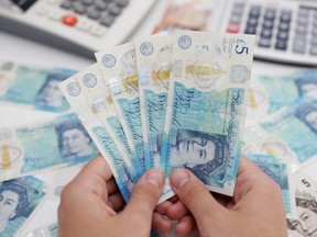 Pound falls to new low as 'mini budget' shatters investor confidence 2 A woman holds British pound banknotes in this illustration taken on May 30, 2022.