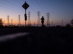 Eine Frau joggt an Stromleitungen vorbei, als sich am 17. August 2022 in Mountain View eine Welle extremer Hitze über weite Teile Kaliforniens legte.