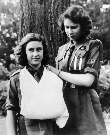 Britain's Queen Elizabeth II, then Princess Elizabeth, right, and Princess Margaret, in their Girl Guide uniforms, practice their bandaging skills in this August 1943 file photo. Princess Elizabeth is wearing the badge of the swallow patrol and two white stripes, which indicates that she is patrol leader.  The Queen will celebrate her 80th birthday on April 21, 2006. (AP Photo)