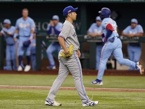 Blue Jays pitcher Yusei Kikuchi, foreground, walks on the field as Texas Rangers' Adolis Garcia, back right, runs the bases after hitting a two-run home run during the third inning in Arlington, Texas, on Sunday, Sept. 11, 2022.
