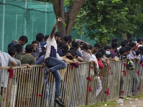 A man jumps a railing to take a break as people line up to buy tickets for the third Twenty20 cricket match between India and Australia at Gymkhana grounds in Hyderabad, India, Thursday, Sept. 22, 2022. Earlier in the day 20 people were injured here in a stampede when sales of tickets opened.