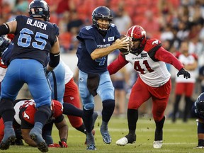 Toronto Argonauts quarterback McLeod Bethel-Thompson (4) tries to evade a tackle by Calgary Stampeders defensive lineman Mike Rose (41) during first half CFL football action in Toronto on Saturday, August 20, 2022. /