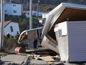 Menschen entfernen Gegenstände aus beschädigten Gebäuden, die nach dem Hurrikan Fiona in Port Aux Basques, Neufundland und Labrador, Sonntag, 25. September 2022, von ihrer Position entfernt wurden.