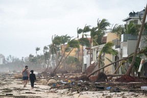 People walk along the beach looking at property damaged by Hurricane Ian in Bonita Springs, Fla., Thursday, Sept. 29, 2022.