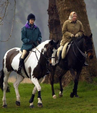 Queen Elizabeth II (R) and her daughter Princess Anne (L) ride in the grounds of Windsor Castle 02 April 2002. (ADRIAN DENNIS/AFP via Getty Images)