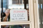 Small business owner attaches permanent close sign on the window due to the pandemic.