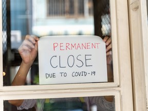 Small business owner attaches permanent close sign on the window due to the pandemic.