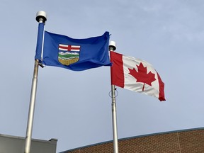 An Alberta Flag with the Canadian flag  during a windy day.