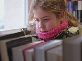 Young girl looking for a book to read in a library.