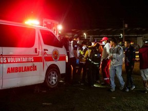 Paramedics and government officials stand at a scene following a stampede at a rock concert to commemorate the country's Independence Day that left people dead and injured, in Quetzaltenango, Guatemala, Thursday, Sept. 15, 2022.