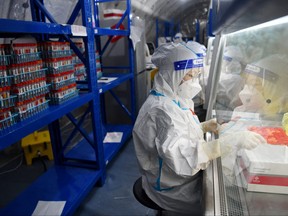 Staff members of Sichuan Provincial People's Hospital test nucleic acid samples inside a mobile laboratory set up at a sports centre, following COVID-19 outbreak in Chengdu, Sichuan province, China, Sept. 4, 2022.