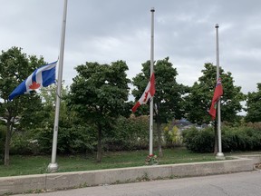 Flowers laid below lowered flags outside Toronto Police Traffic Services on Tuesday, Sept. 13, 2022 following the murder of Const. Andrew Hong.