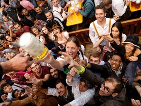 People reach out for a pint of beer during the official opening the world's largest beer festival, the 187th Oktoberfest in Munich, Germany, September 17, 2022.