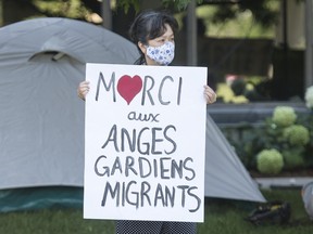 In this file photo taken on Aug. 1, 2020, a woman takes part in a sit-in protest outside Prime Minister Justin Trudeau's constituency office in Montreal, where protesters called on the government to give residency status to all migrant workers and asylum seekers.