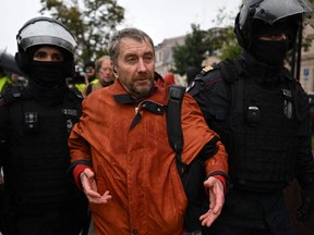 Police officers detain a man in Moscow on Saturday, Sept. 24, 2022, following calls to protest against the partial mobilization of military reservists announced by Russian President Vladimir Putin.