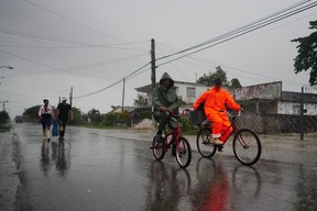 People walk under the rain ahead of the arrival of Hurricane Ian in Coloma, Cuba, Sept. 26, 2022.