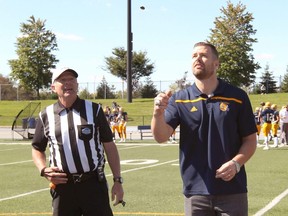 Referee Alex Gyemi (left) watches former University of Windsor running back Daryl Stephenson conduct the coin toss before a U Sports football game in 2018.