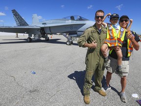 Marky "M-Dog" Czutrin, aged 8, poses with his grandad Gerry Seetner and Capt. Jesse Haggart-Smith showing off his "guns in front of the RCAF's CF-18 Hornet Demonstration fighter jet as part of the Canadian International Air Show preview on Thursday September 1, 2022. Jack Boland/Toronto Sun