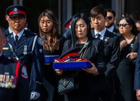 The wife of slain Const. Andrew Hong, Jenny, holds his hat, at the end of his funeral. Behind are daughter Mia, 17, and son, Alex, 15, at the Toronto Congress Centre on Sept. 21, 2022. Ernest Doroszuk/Toronto Sun/Postmedia