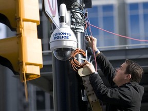 A member of the Toronto Police Video Services Unit tweaks a camera mounted above Yonge and Dundas Square in the heart of Toronto.